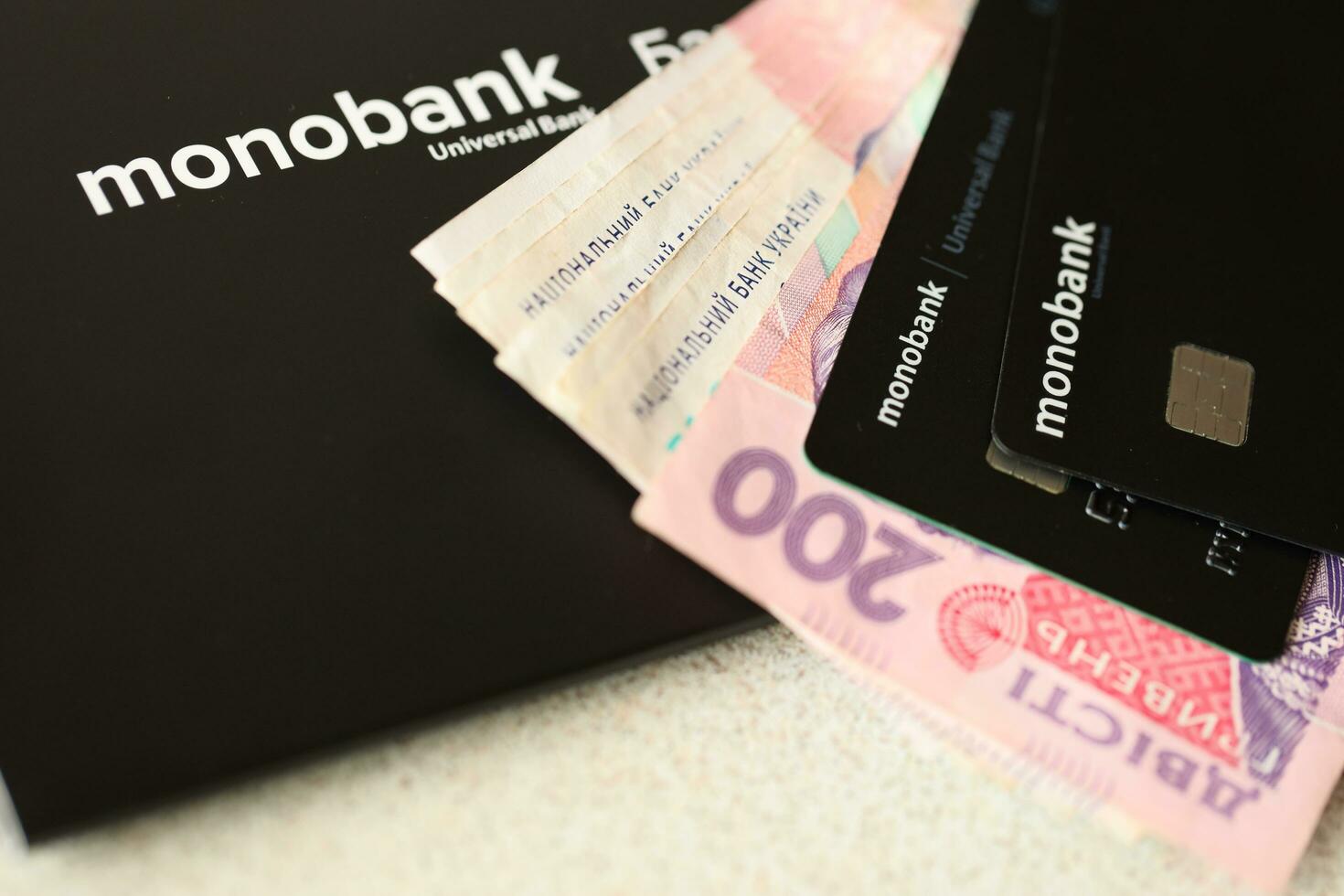 KYIV, UKRAINE - JULY 7, 2023 Monobank banking plastic cards with money on table photo