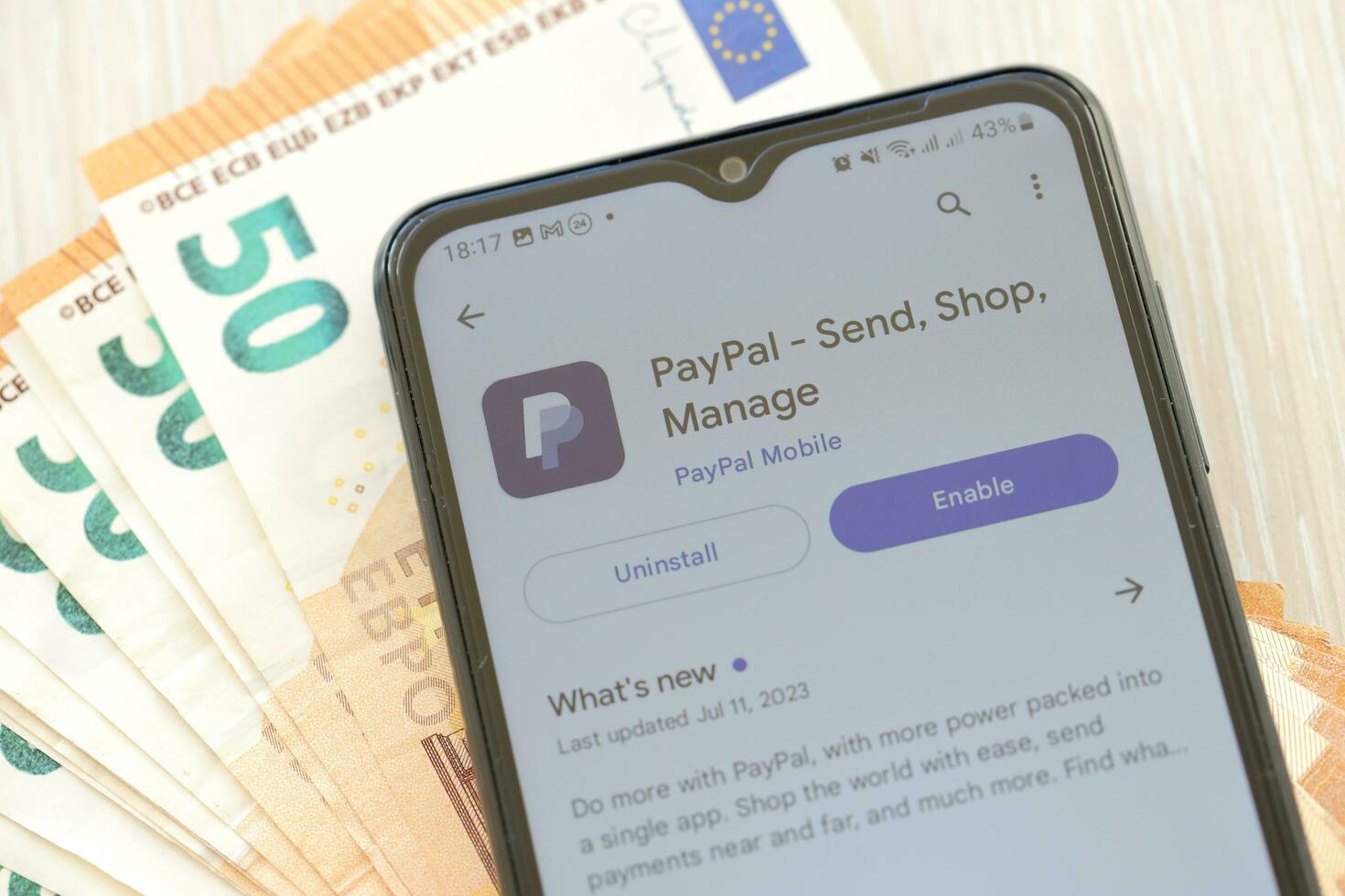 TERNOPIL, UKRAINE - AUGUST 3, 2023 PayPal application on screen on modern smartphone and many bills of euro currency photo