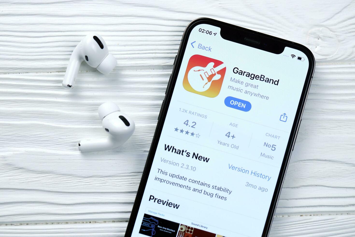 KHARKOV, UKRAINE - MARCH 5, 2021 Garageband for artists icon and application from App store on iPhone 12 pro display screen with airpods pro on white table photo