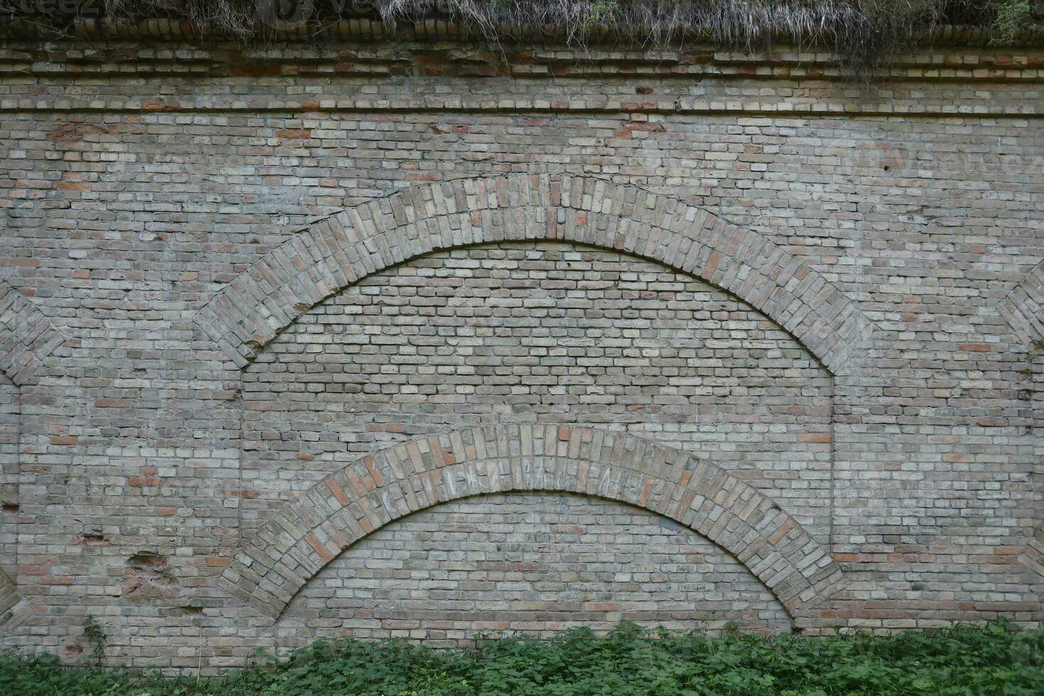 Very old brick stone wall of castle or fortress of 18th century. Full frame wall with obsolete dirty and cracked bricks photo