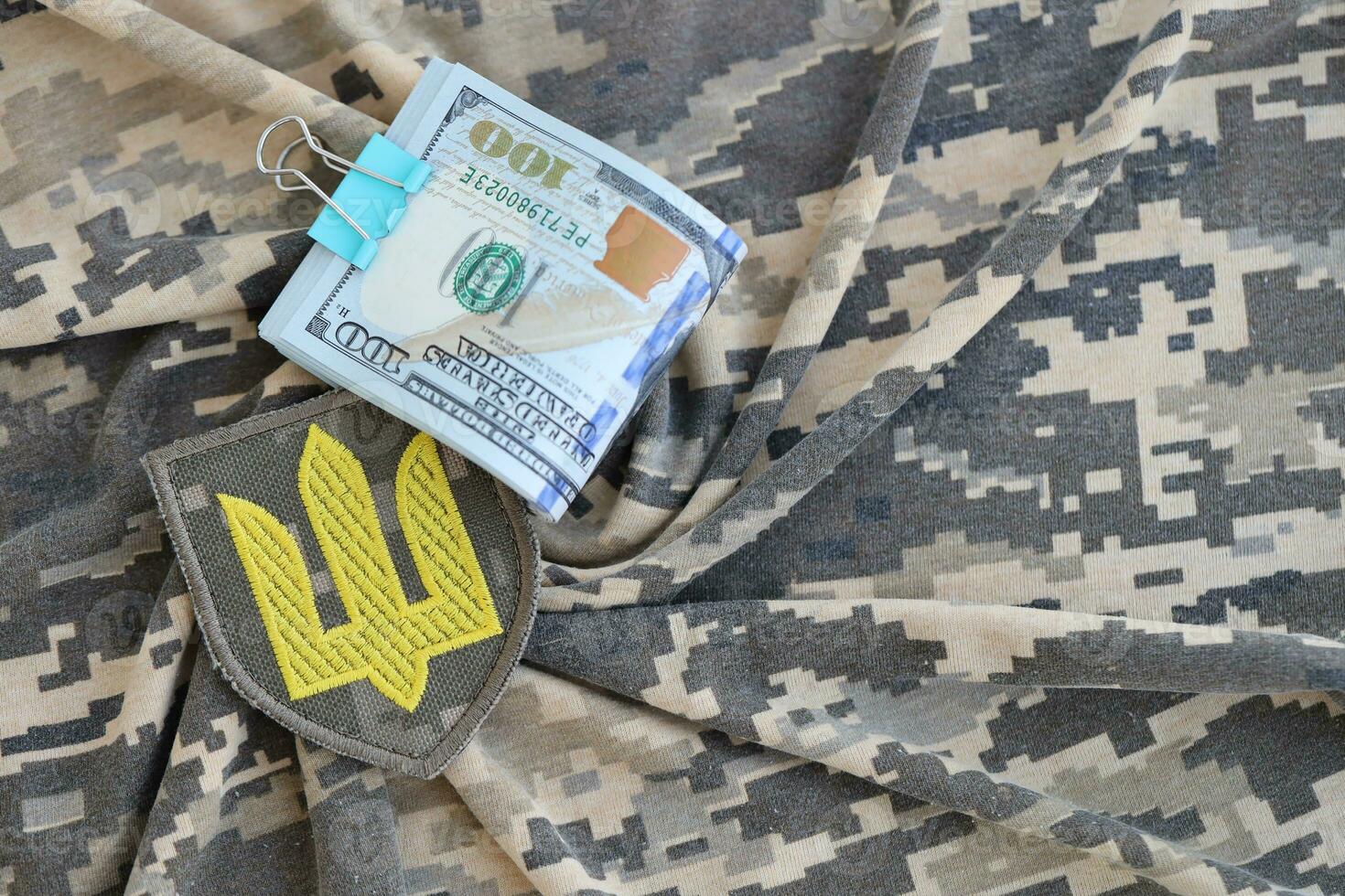 Ukrainian army symbol and bunch of dollar bills on military uniform. Payments to soldiers of the Ukrainian army from United States, salaries to the military. War support photo