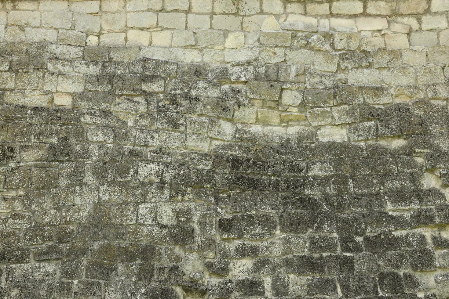Very old brick stone wall of castle or fortress of 18th century. Full frame wall with obsolete dirty and cracked bricks photo