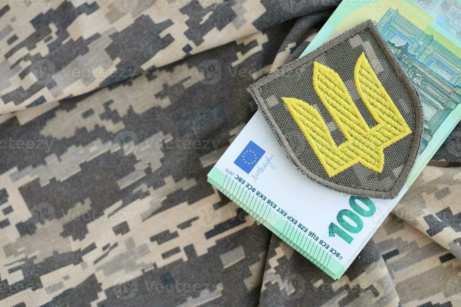 Ukrainian army symbol and bunch of euro bills on military uniform. Payments to soldiers of the Ukrainian army from European union, salaries to the military. War support photo