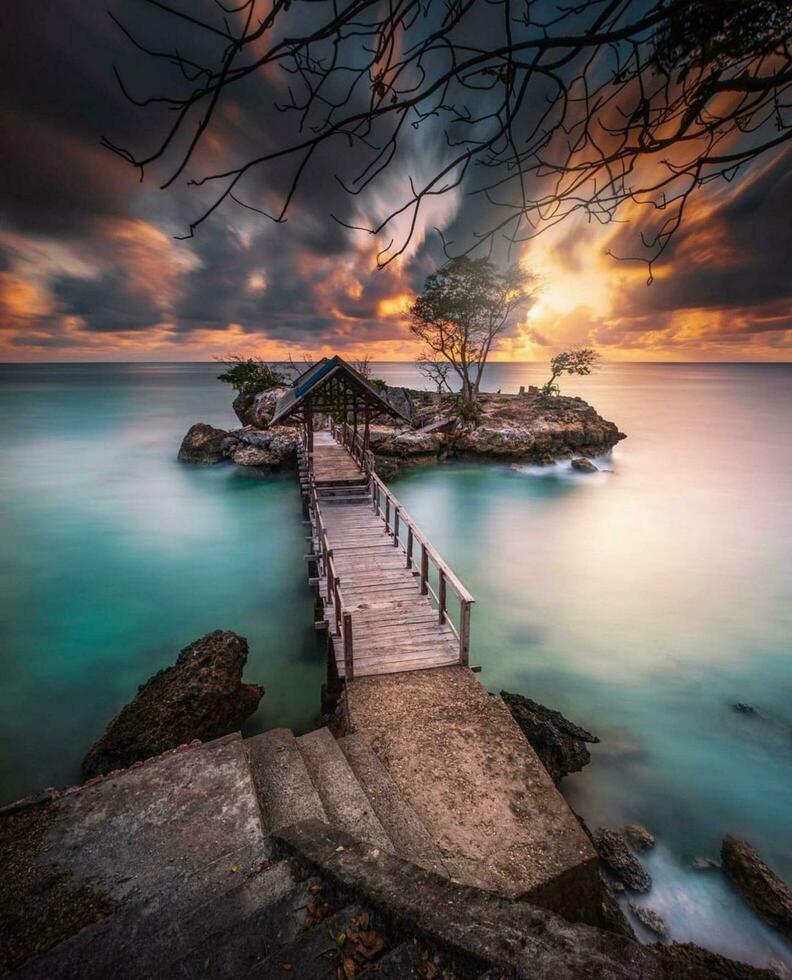 The Serene Beauty of the Coast at Sunset, in Indonesia, South Sulawesi,Tranquil beach sunset with calm ocean, vibrant sky, and solitary tree. photo