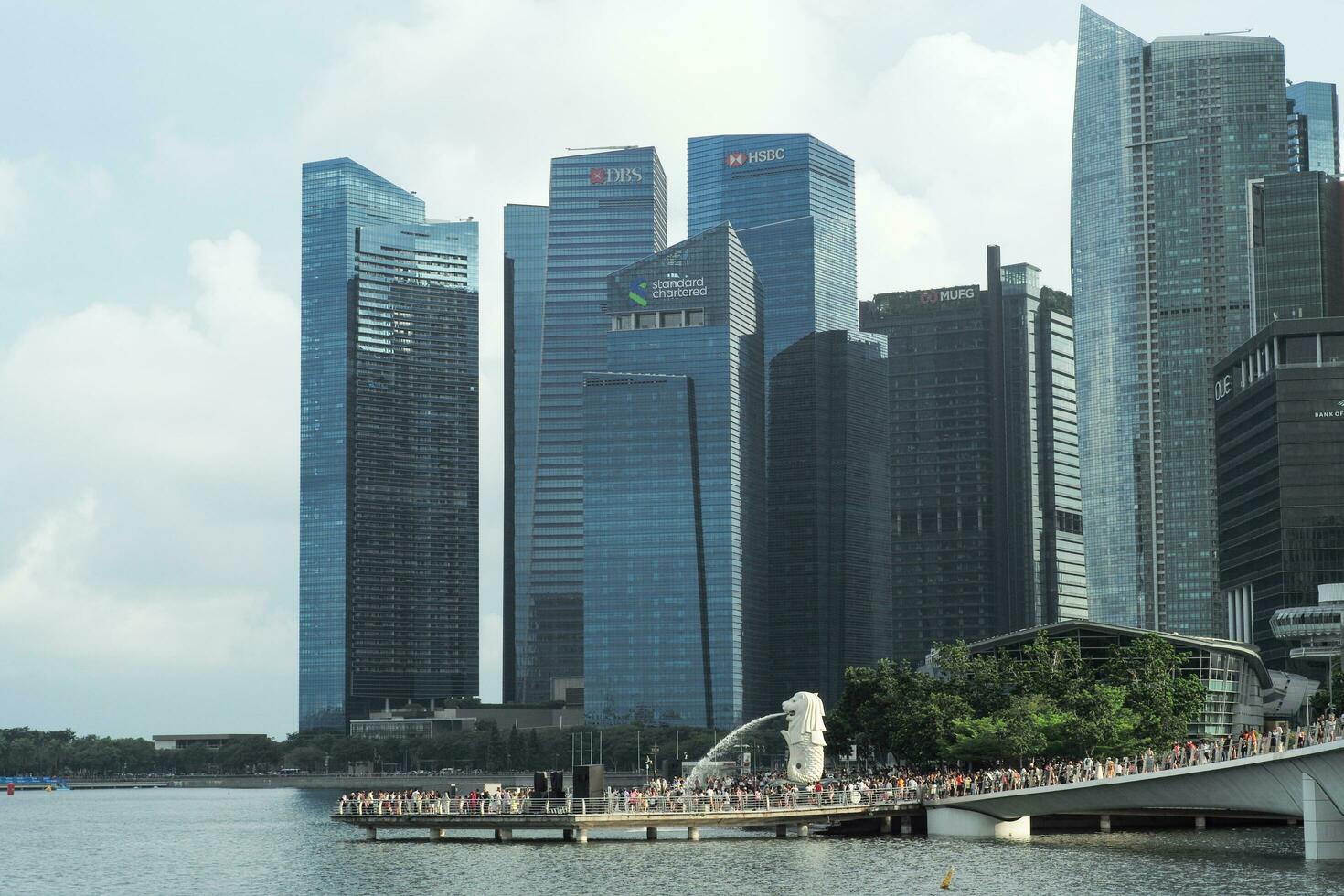 Singapore, August 19, 2023-Group of people walking on the walkway to Merlion with crowded of high modern buildings in background photo