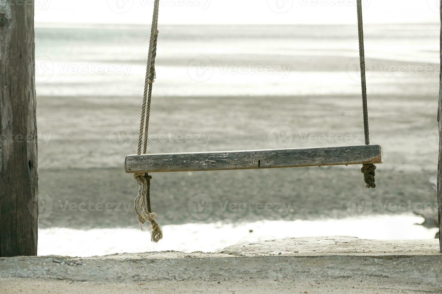 Wooden swing hanging from the bar with beach background photo