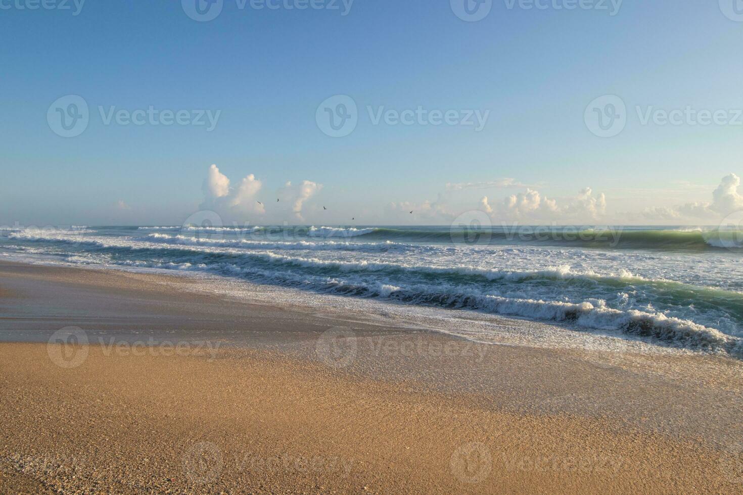 Waves breaking on sandy beach photo