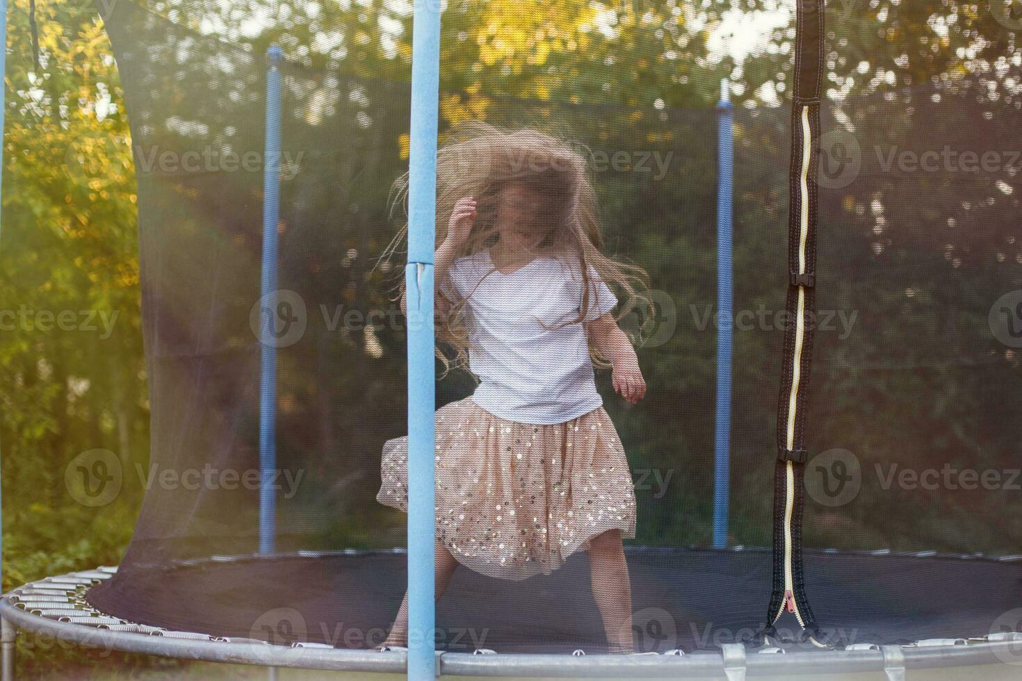 Little child girl jumping on the trampoline in the back yard photo