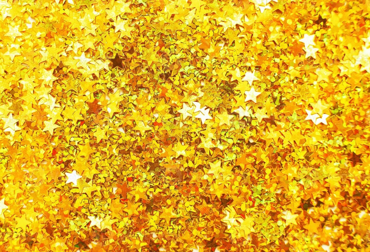 Glittering background of golden sequins in form of stars closeup. Sparkle festive texture. photo