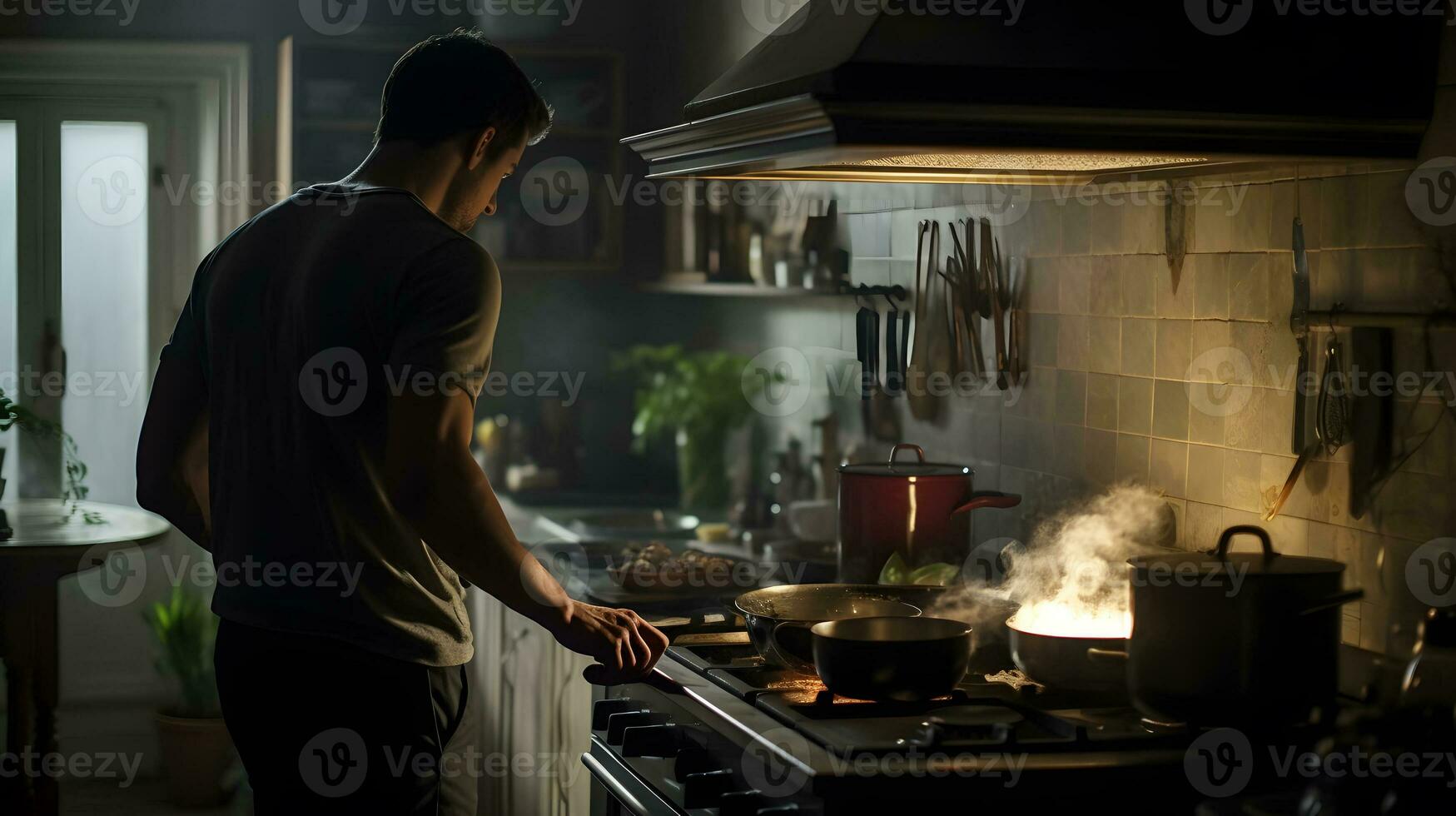 Young man cooking in the kitchen at night, he is preparing food photo