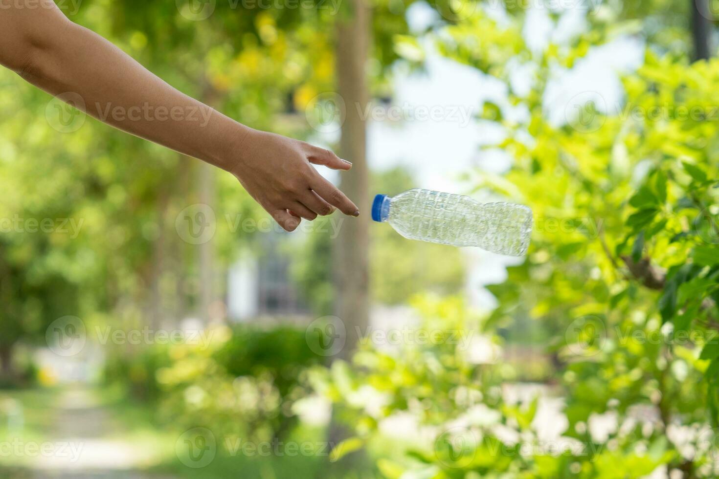 Photo of hands throwing away plastic bottles in nature