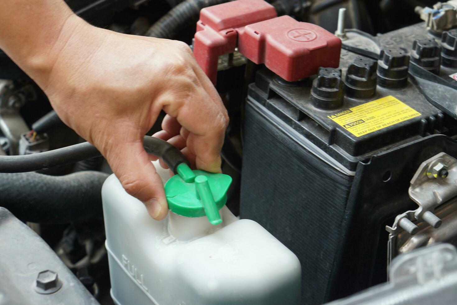 Closeup hand hold bottle tank of car engine coolant. Concept, automobile maintenance. Check and repair before driving for safety. Basic diagnose vehicle problems. photo