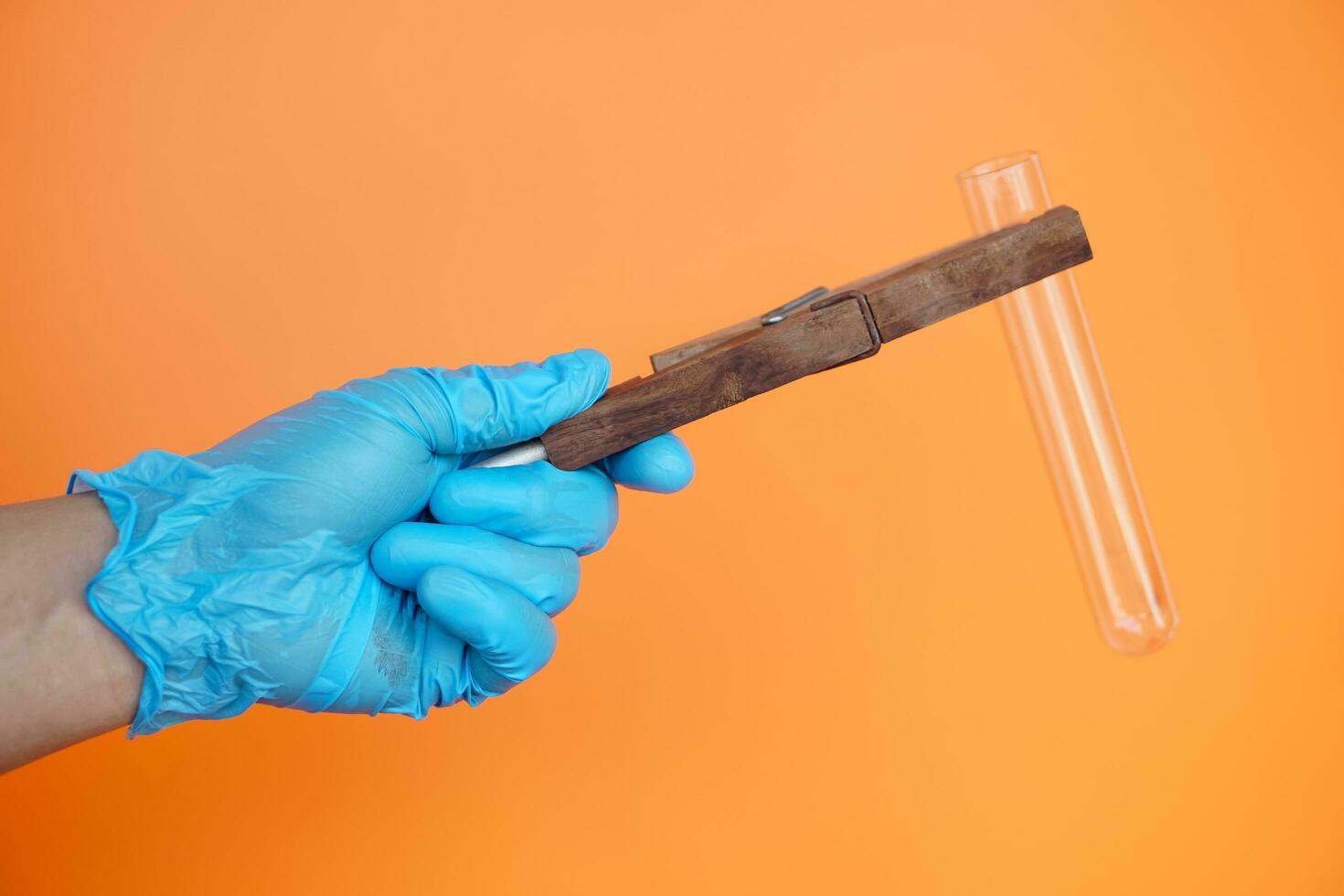 Close up hands wears blue glove, hold wooden tong to hold transparent test tube. Concept, science tool for doing experiment. Education. Science subject. Learning by doing. photo