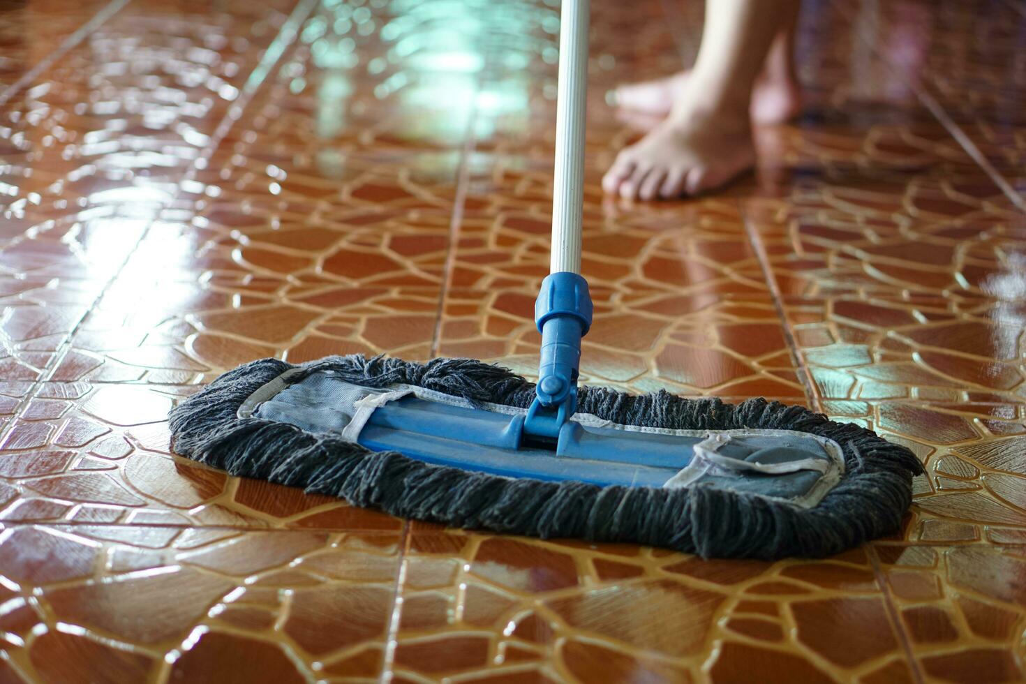 Close up man use a mop to mop the floor. Concept, household chore in daily life. Hygienic and sanitary. Mop the dust, wipe the floor. Cleaning house. Maintaining tile floors to be clean and shiny photo