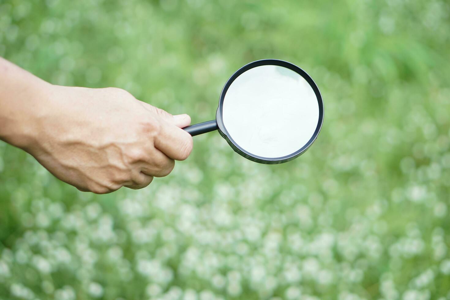 Close up hand holds magnifying glass. Concept, search for tiny things for collecting data or information to study or research. Explore or investigate from clue or evidence photo