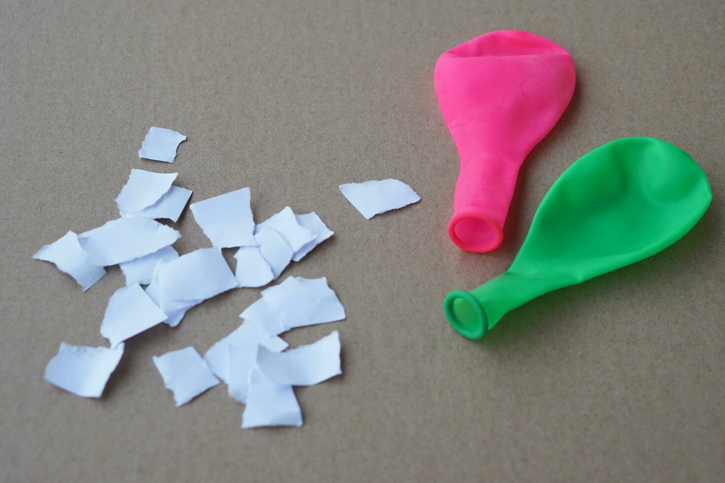 Green and pink balloon with no air and small pieces of paper. Concept, Science project work activity.Prepare for doing fun and easy experiment about static electricity. photo