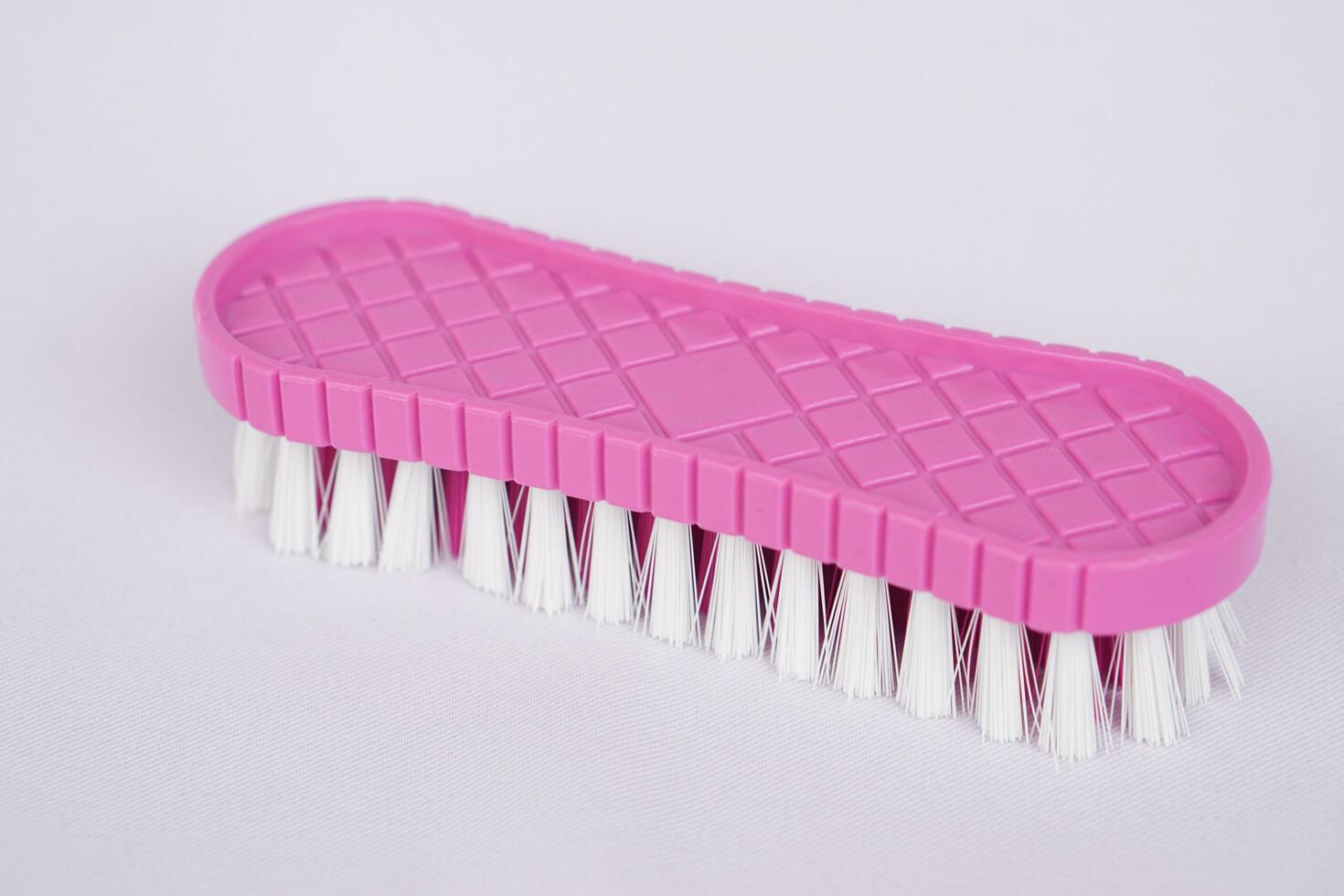 Pink brush made of plastic and nylon for washing cloth or cleaning floor on white background. Concept, equipment for washing, scrubbing and cleaning dirty cloth, carpet or surface. Daily chores tool. photo