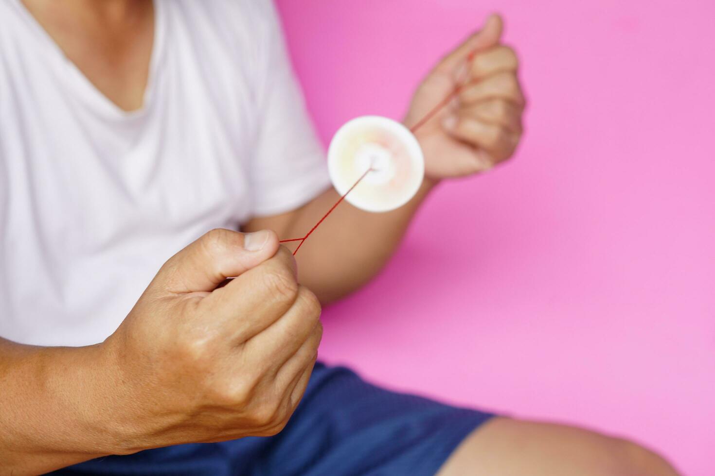 Closeup man hand plays the diy spinning wheel toy, made from bottle cap and string. Spinning motion photo. Concept, retro toy which apply with science knowledge. Potential energy photo