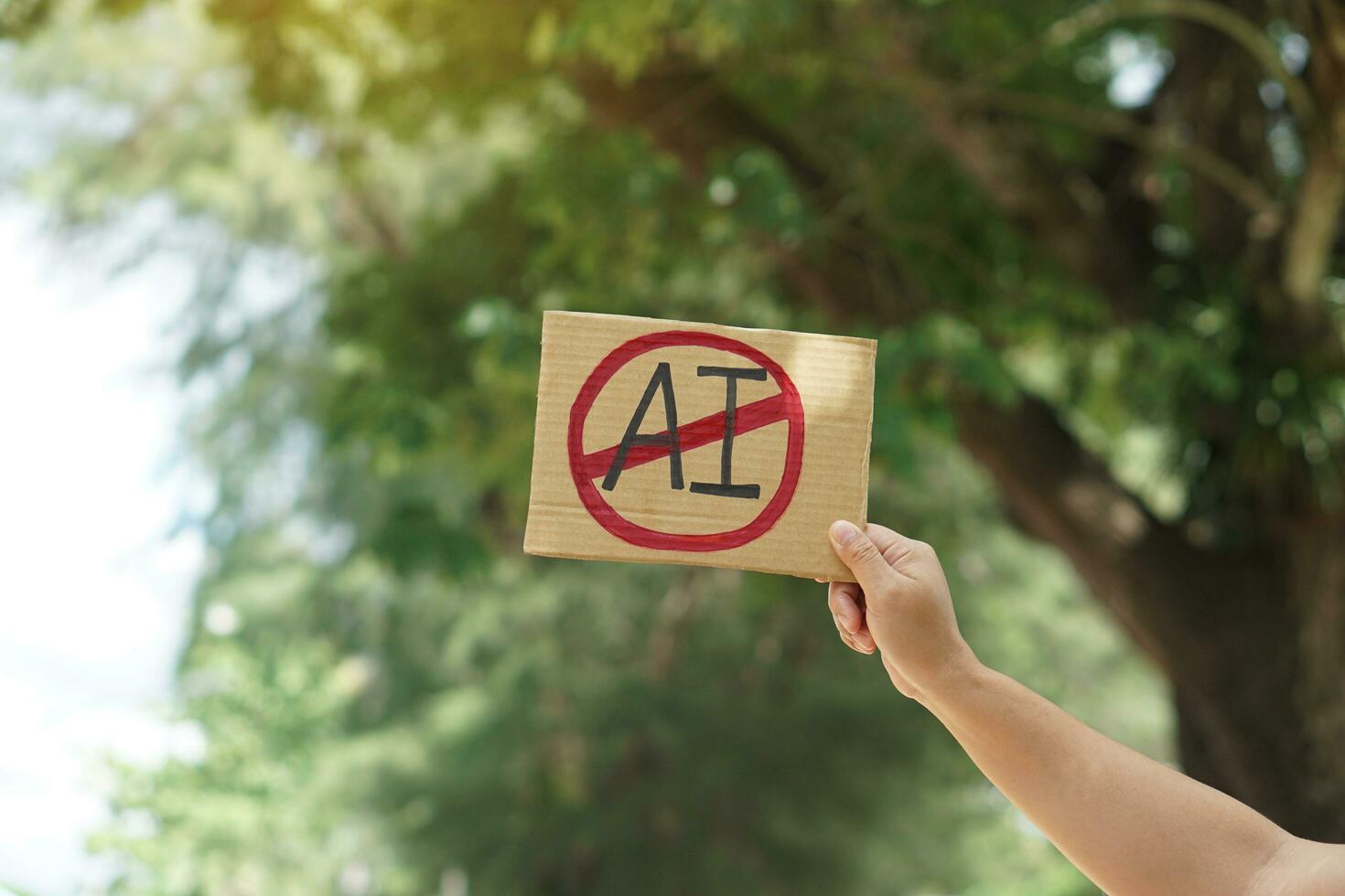 Close up hand holds paper card with No AI,  prohibition sign, outdoor nature background. Concept, disagree, anti or don't support to use AI or Artificial Intelligence in daily life. photo