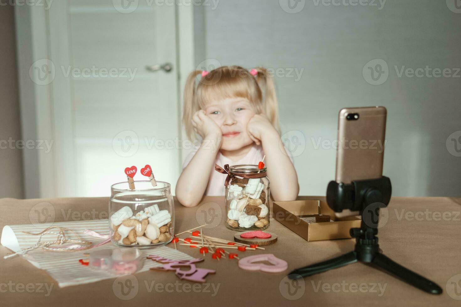 un pequeño niña blogger hace un dulce San Valentín día regalo con su propio manos. un regalo para el día festivo, un vídeo Blog entrada. foto