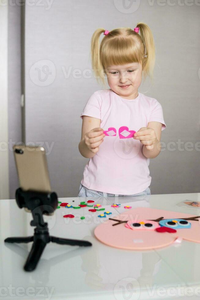 A blogger girl makes a felt craft for Valentine's Day in the shape of a heart. The concept of children's creativity and handmade. photo