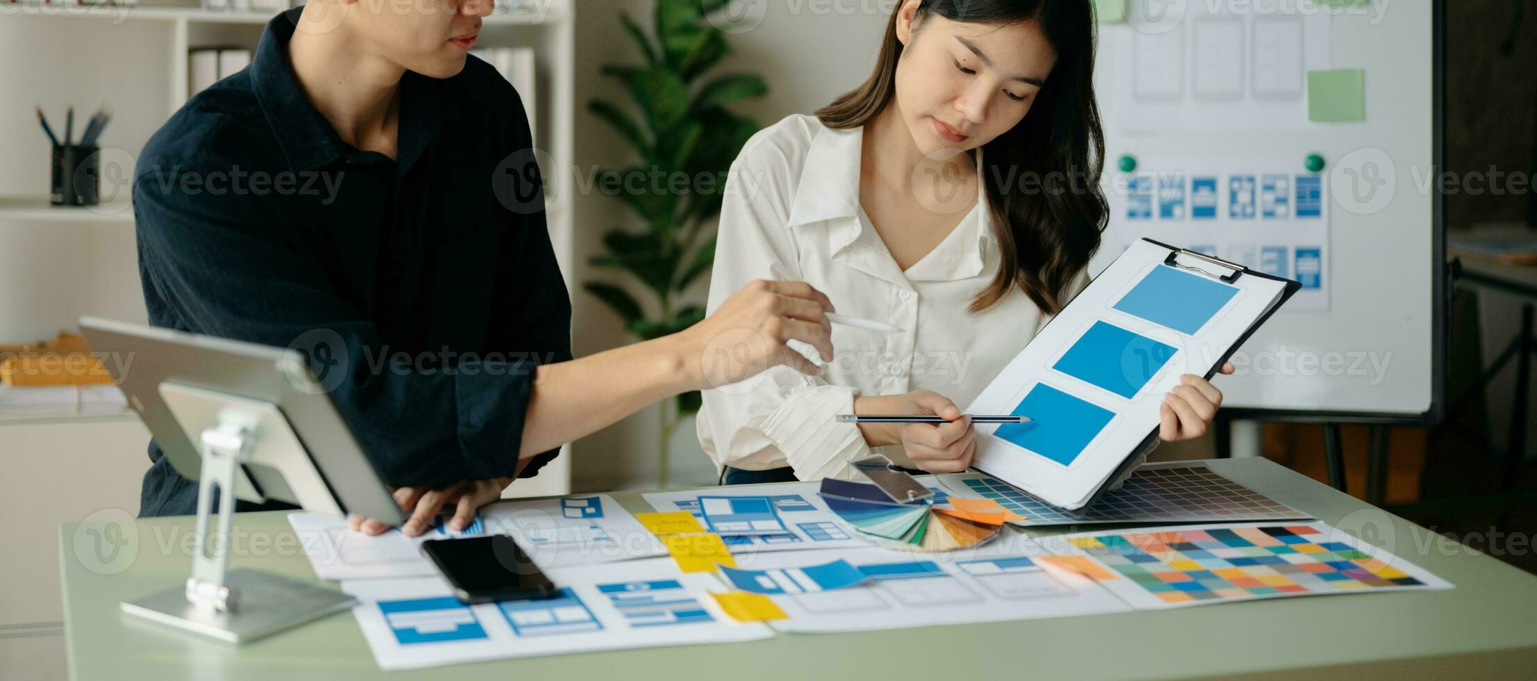 UX developer and ui designer brainstorming about mobile app interface wireframe design with customer breif and color code at office. photo