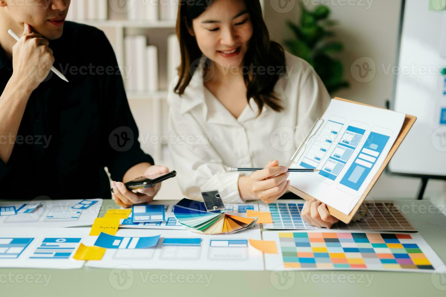 UX developer and ui designer brainstorming about mobile app interface wireframe design with customer breif and color code at office. photo