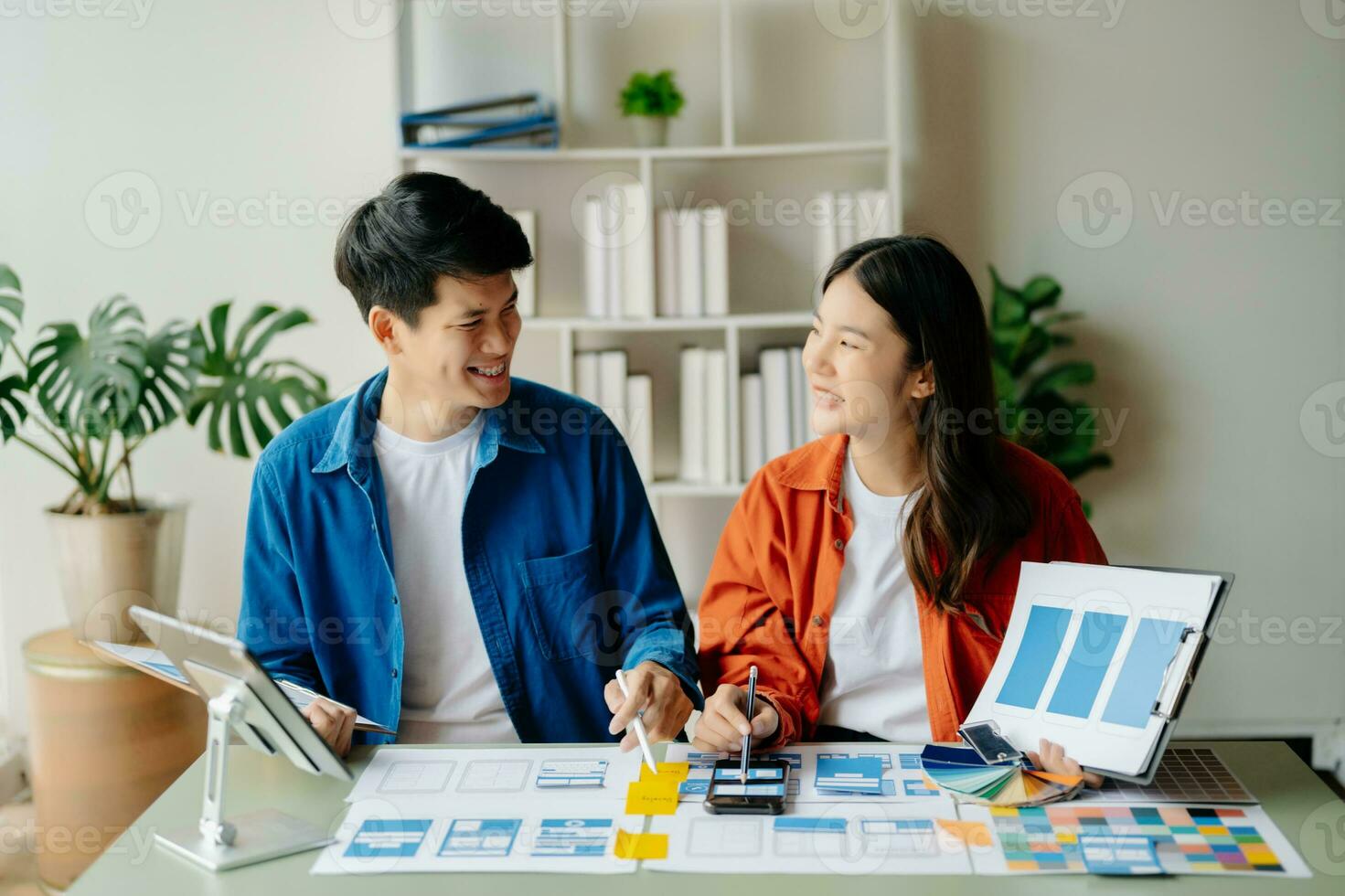UX developer and ui designer brainstorming about mobile app interface wireframe design with customer breif and color code at office. photo