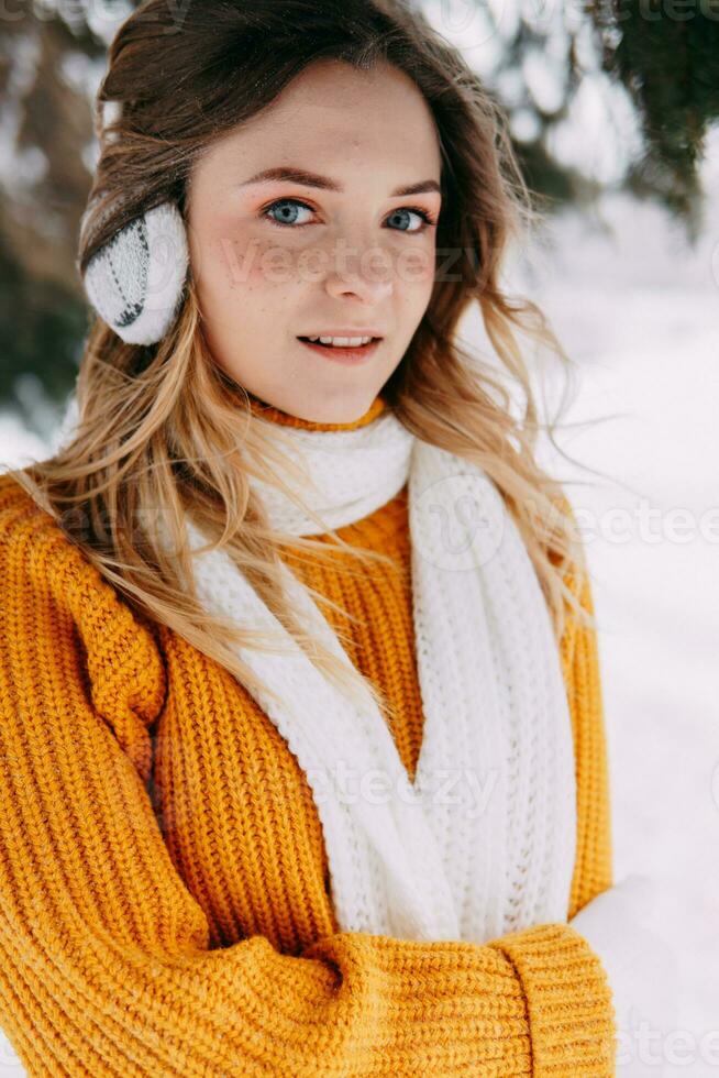 Teen blonde in a yellow sweater outside in winter. A teenage girl on a walk in winter clothes in a snowy forest photo