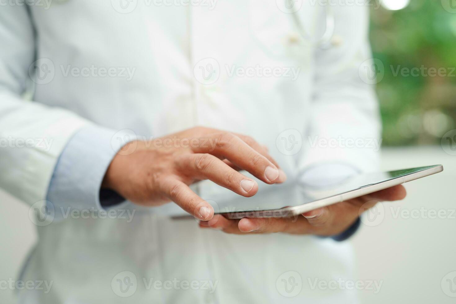 Asian man doctor using tablet computer to reading patient report, check up and search for solve treatment health medical online in hospital. photo