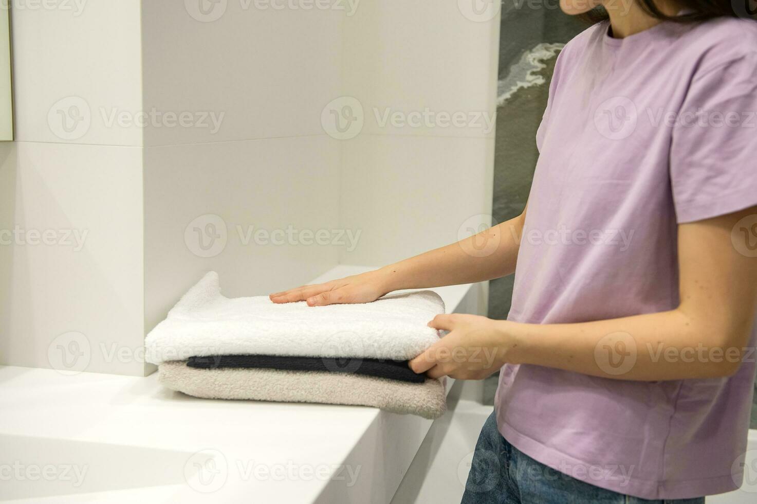 The girl's hands are straightening folded terry bath towels photo