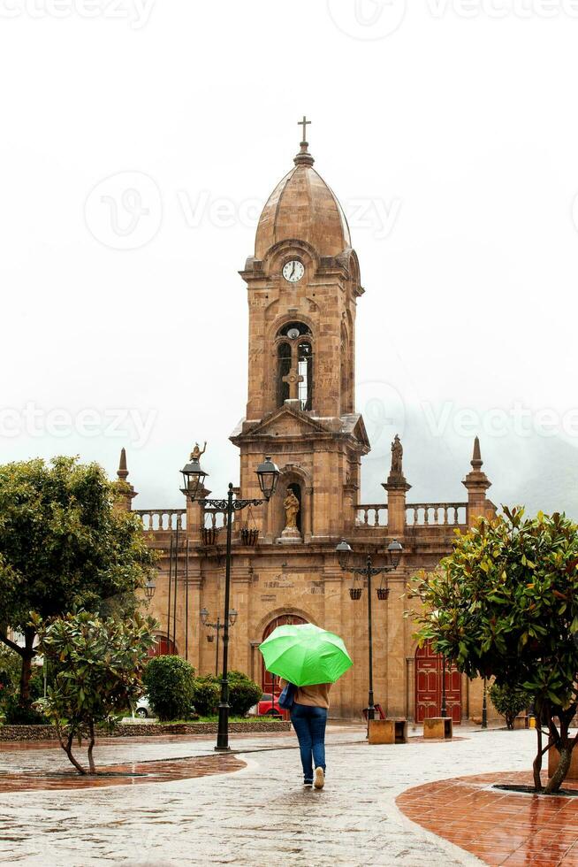 mujer caminando con un paraguas a el hermosa central cuadrado ade el pequeño pueblo de nobsa en un lluvioso día foto