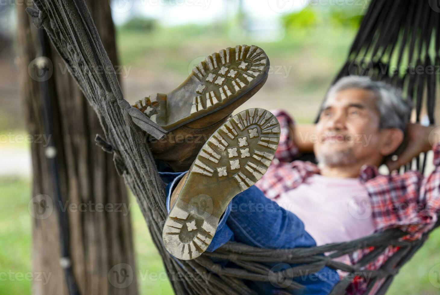a male legs in boots on rope hammock background nature, happy mature man lying on a hammock at resort garden on summertime,concept of people holidays,travel,camping,adventure photo