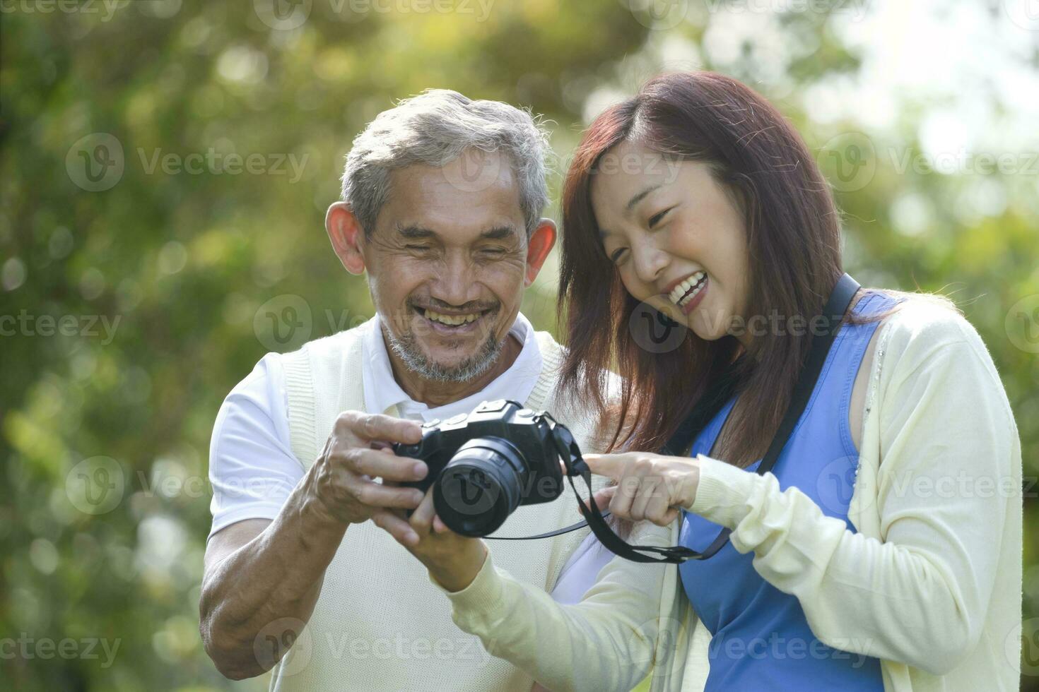 joven asiático hija disfrutar al aire libre actividad juntos con retirado mayor padre, ellos son mirando a imágenes en un cámara, concepto familia relación, estilo de vida, relajante, viaje foto