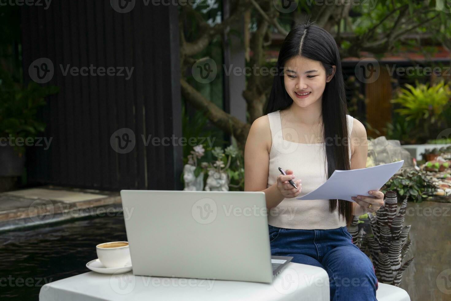 young attractive asian woman working over laptop at resting zone in the resort garden during travel on vacation, concept of digital nomad,travel freely,working remotely on internet online photo
