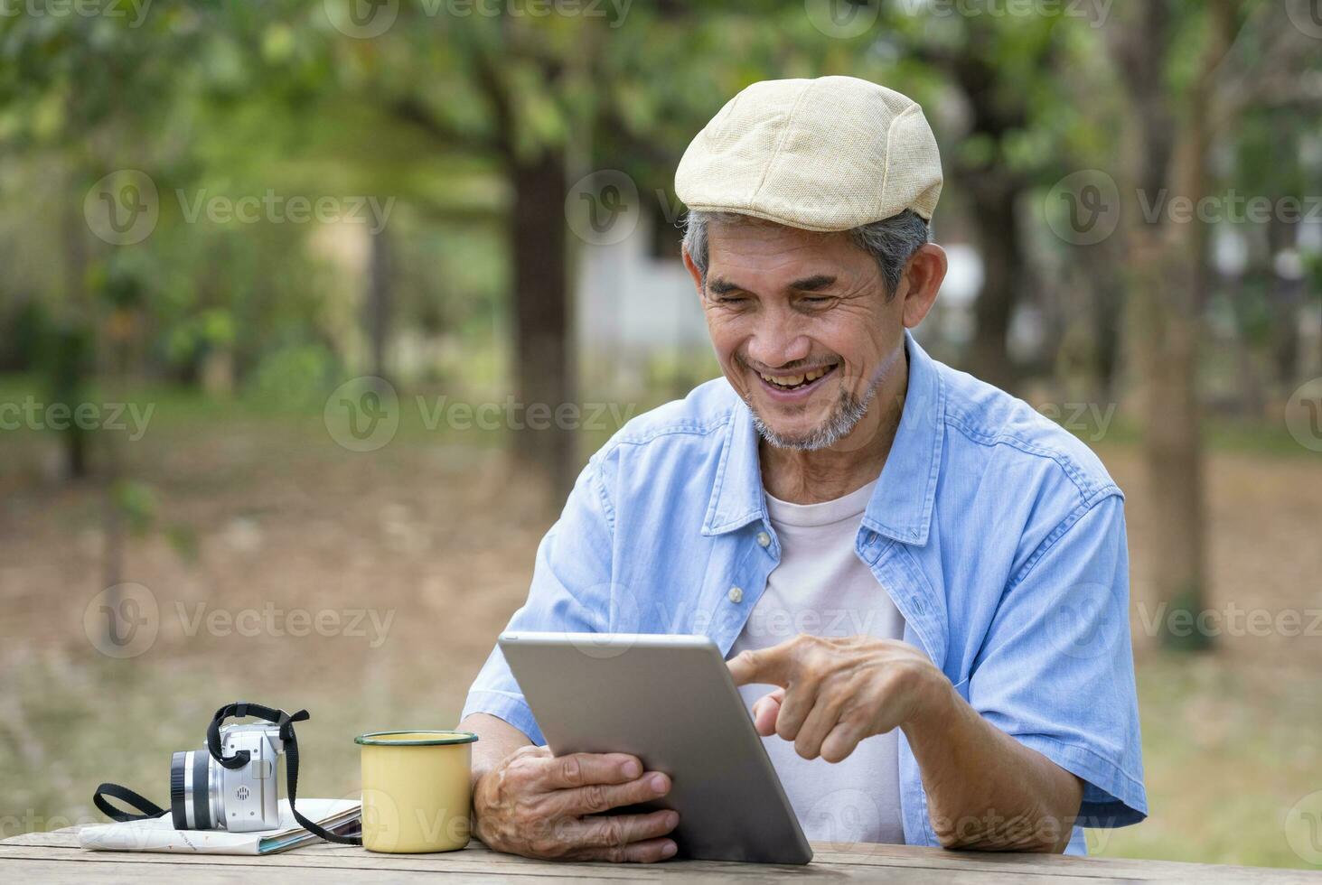 portrait happy senior man using online internet tablet searching direction for his journey while resting in the national park,concept of elderly people using technology for travel photo