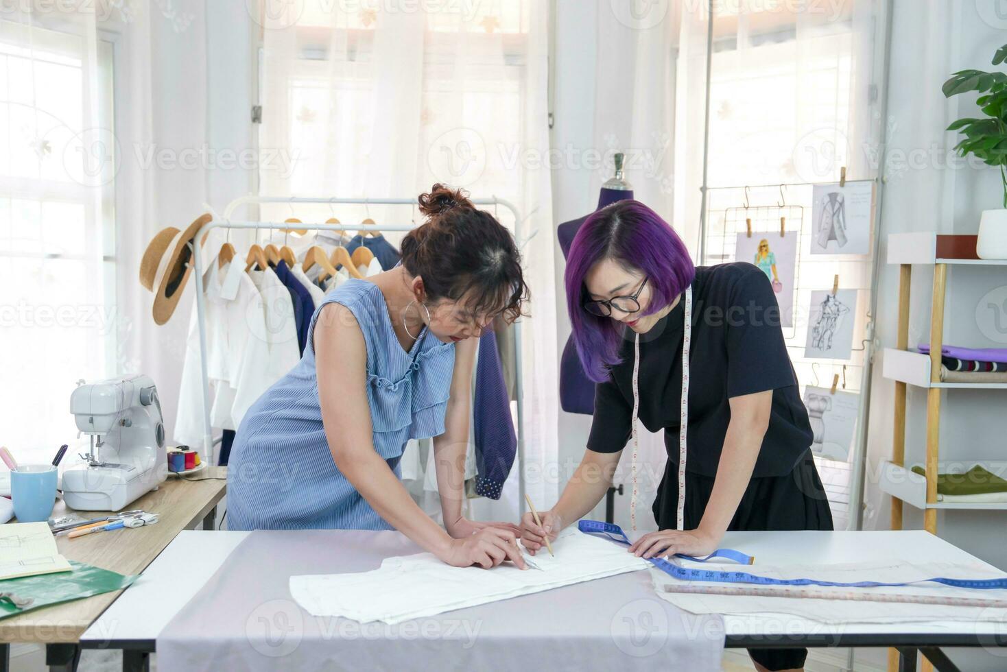 young confident female designer in purple color hair discussing about clothes pattern with tailor at fashion studio, concept of business,industry,design,tailoring photo