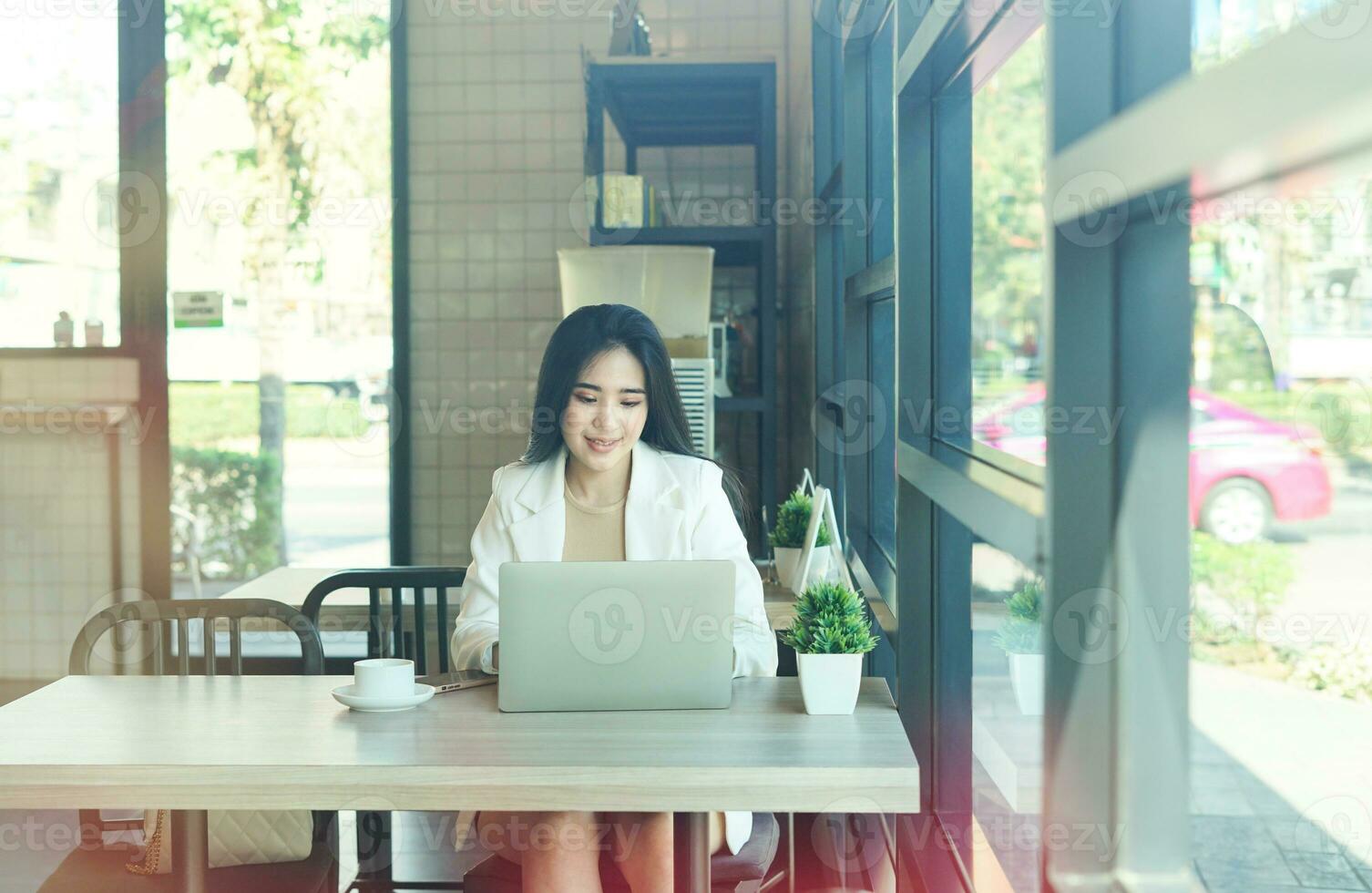 business woman working casually with laptop in the coffee shop view through the glass window photo