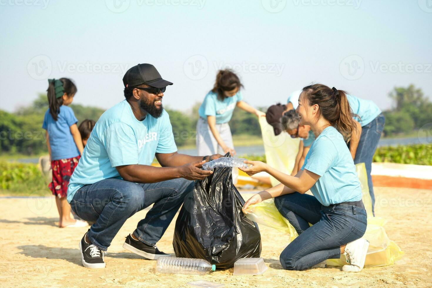 A diverse group of volunteers join together to cleanup the sand beach,collect garbage,separate waste.concept of global warming issue,reduce the impact of waste on the environment,save the planet photo