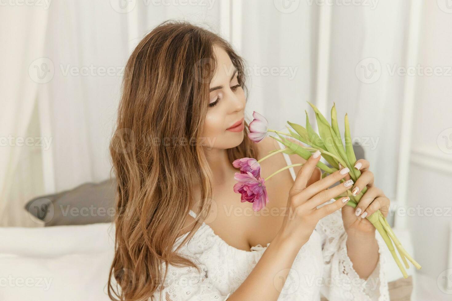 A brown-haired woman with long hair is having breakfast at the table with croissants and a cup of coffee. Spring portrait. photo