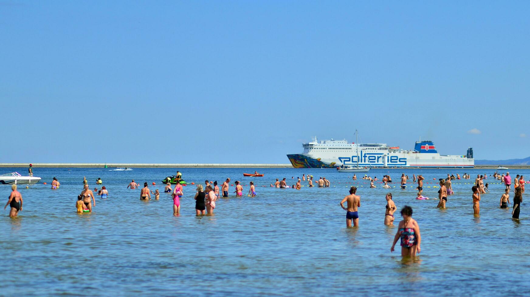 Swinoujscie, Poland. 15 August 2023. People in the water on the beach during holiday season in over Baltic Sea. photo