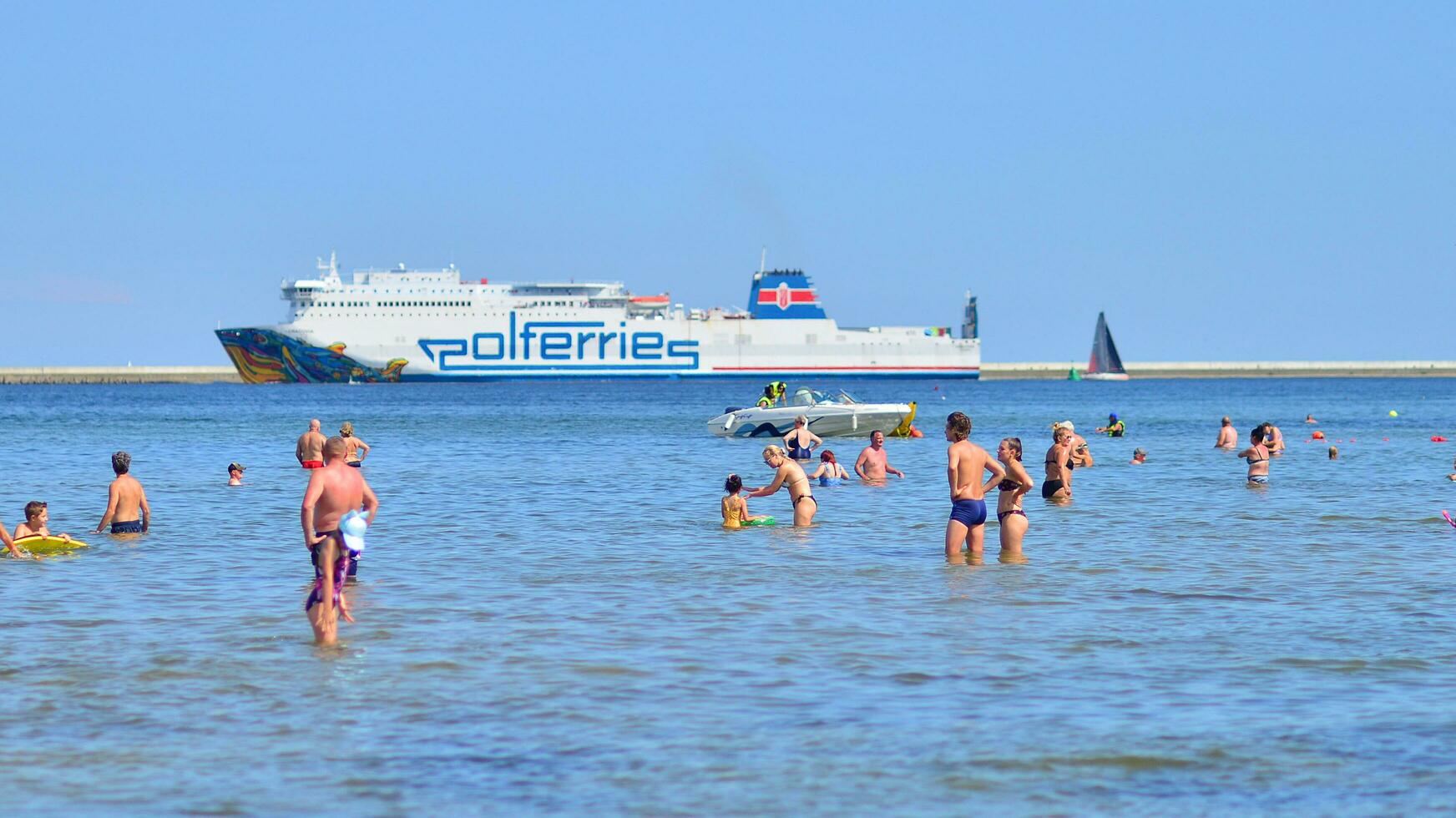 Swinoujscie, Poland. 15 August 2023. People in the water on the beach during holiday season in over Baltic Sea. photo