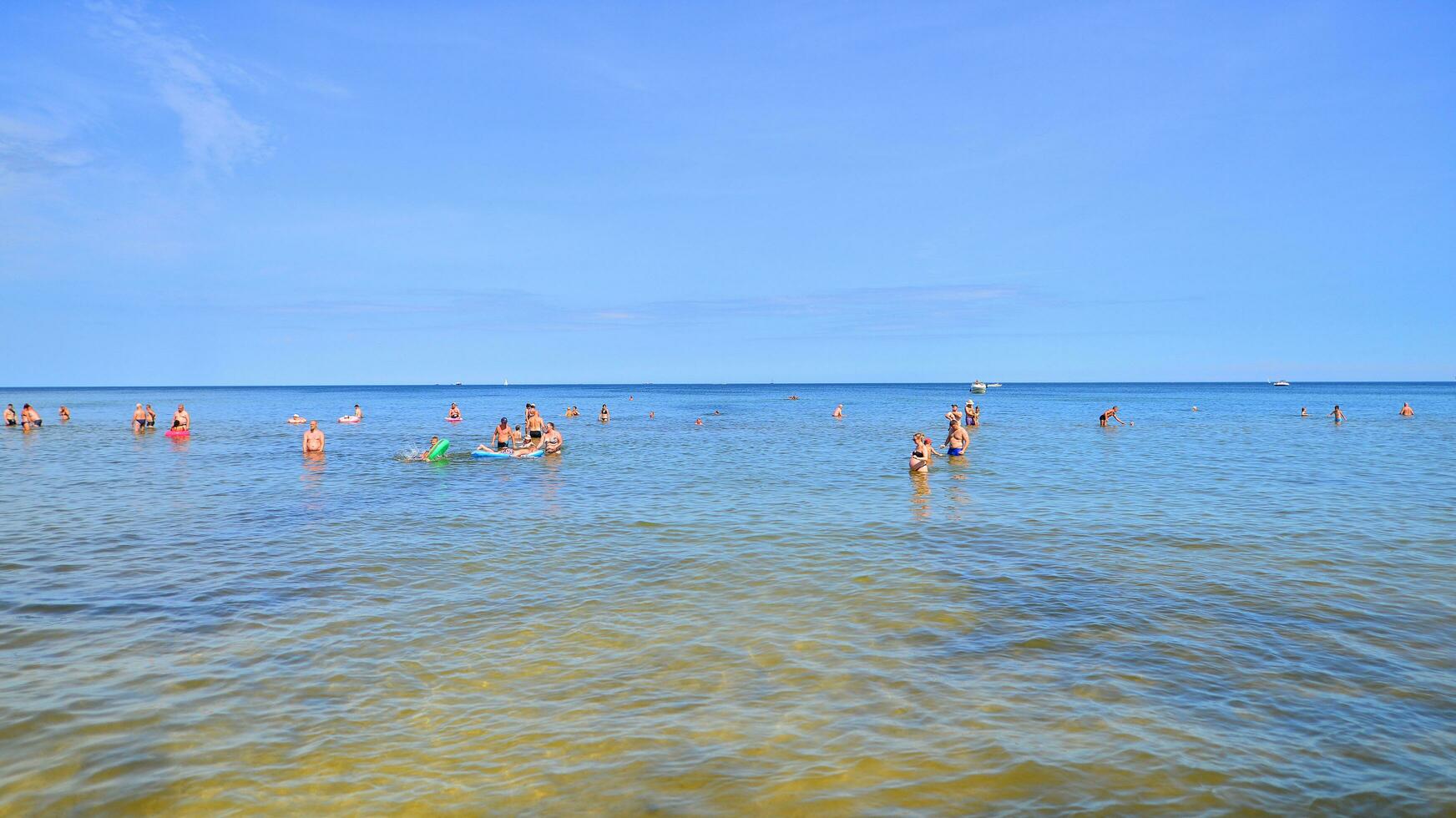 Swinoujscie, Poland. 15 August 2023. People in the water on the beach during holiday season in over Baltic Sea. photo