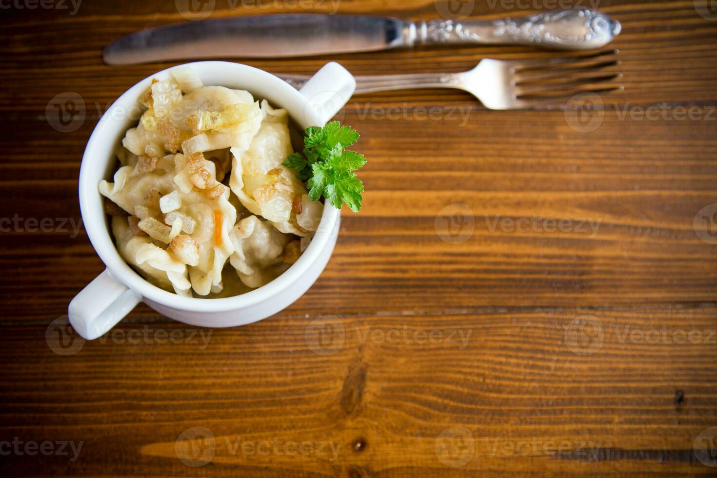 cooked dumplings with potatoes and fried onions on a wooden table. photo