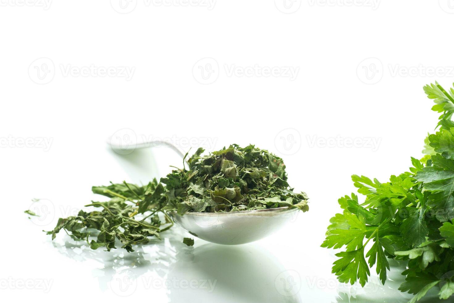 dried parsley in a spoon next to fresh herbs. photo