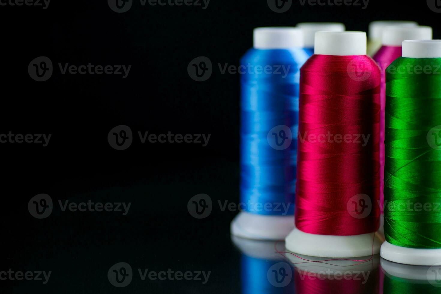 set of different color sewing threads,on black background. photo