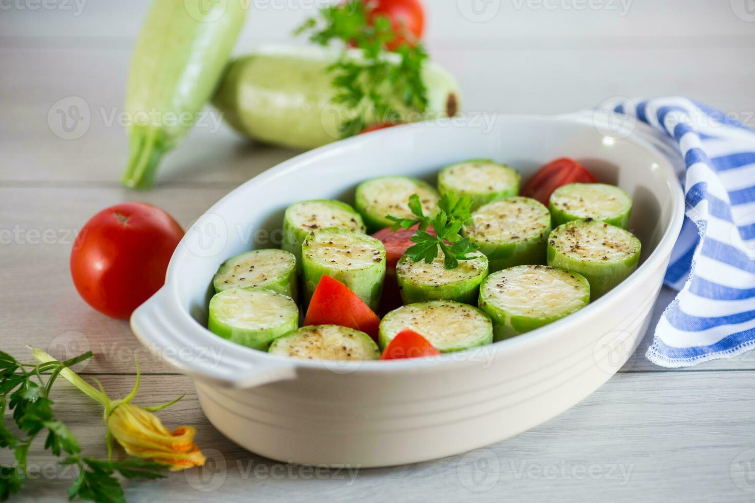 Raw zucchini with tomatoes prepared for baking in a ceramic form. photo