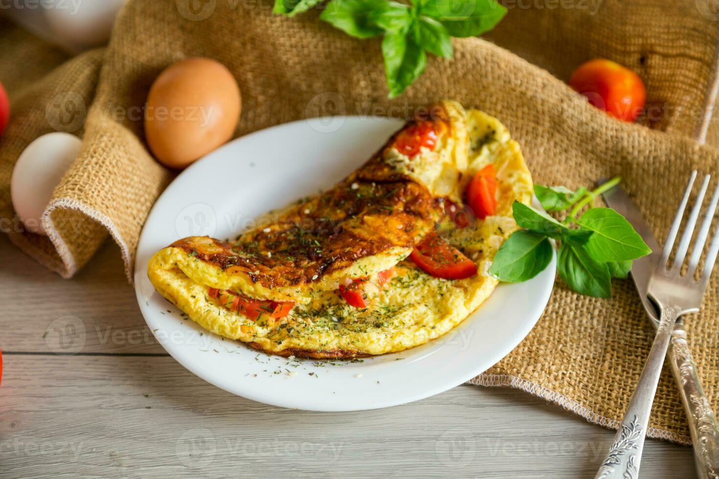 Stuffed omelette with tomatoes on a light wooden background. photo