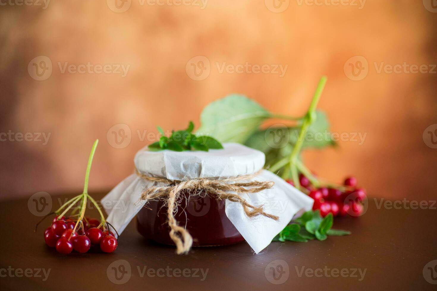 viburnum jam in a glass jar and fresh red viburnum. photo