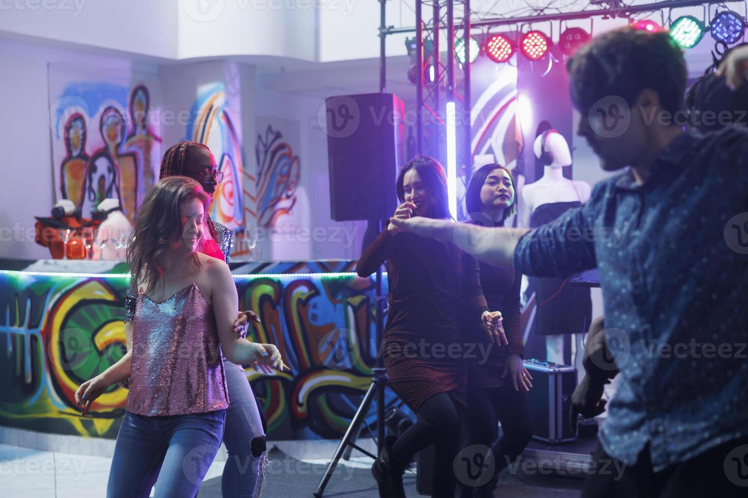 Man and woman dancing and partying at disco gathering in nightclub. Young caucasian couple improvising and making moves on dancefloor while clubbing and attending discotheque photo
